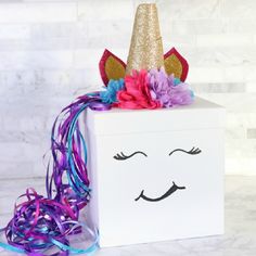 a box with a unicorn face painted on it and some streamers around the edges