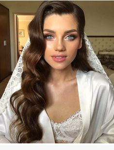 a woman with long hair wearing a white robe and veil, posing for the camera