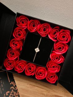 a black box with red roses in it and a white diamond necklace on the inside