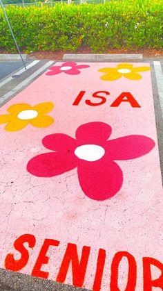 the sidewalk has flowers painted on it and is next to a street sign that says senior