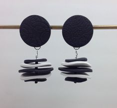 two pairs of black and white earrings hanging from hooks