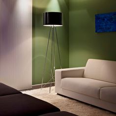 a living room with green walls and a white couch next to a black floor lamp