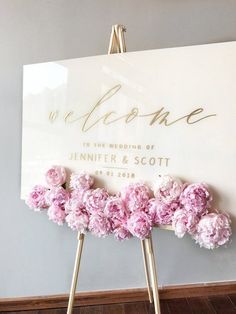 a sign with pink flowers on it in front of a wall