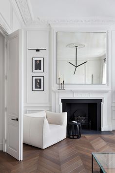 a living room with white furniture and a fireplace in the center, framed pictures on the wall