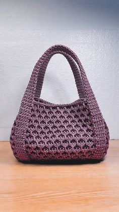 a purple purse sitting on top of a wooden table