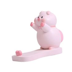 a small pink toy animal on top of a white surface with one hand up in the air