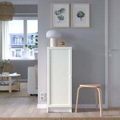 a white cabinet sitting in the middle of a living room next to a chair and table