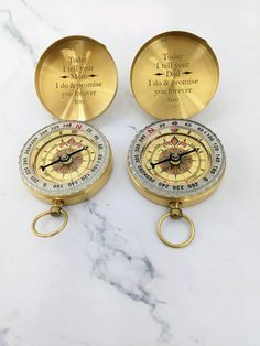 two brass compasss with engraved words on them