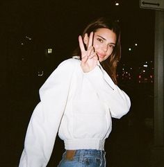 a woman making the vulcan sign with her hand in front of her face at night