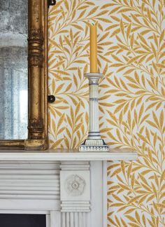 a white fireplace with a gold leaf wallpaper and a mirror on the mantel