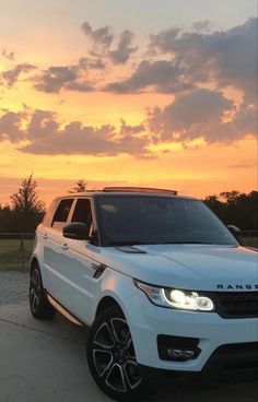 a white range rover parked in front of a sunset