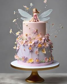 there is a cake decorated with flowers and a fairy figurine on the top