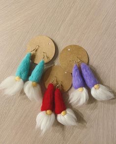 four different colored tasseled earrings sitting on top of a wooden table next to each other