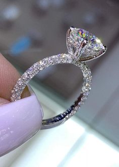 a close up of a person's hand holding a diamond ring