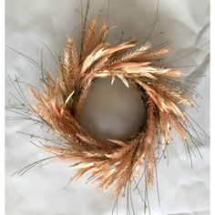 a dried wreath is shown on a white sheet with some grass in the middle and brown stems sticking out of it