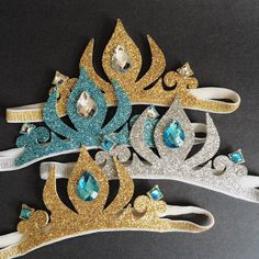 three tiaras with blue, gold and silver jewels on top of each one in the shape of a crown