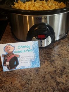 a crock pot with macaroni and cheese in it next to a business card