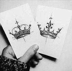 two cards with crowns drawn on them are being held up by someone's hand