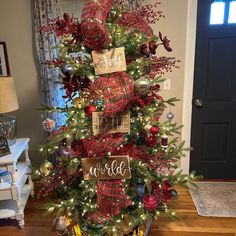 a christmas tree decorated with red and green plaid ribbon, ornaments and name tags on it