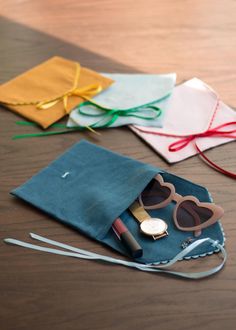 several pieces of clothing and accessories are laid out on a wooden table, including sunglasses