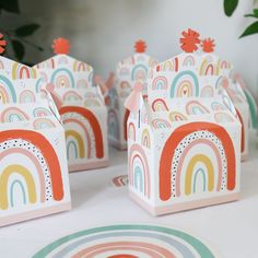 small boxes with rainbow designs on them sitting on top of a table next to plates and flowers