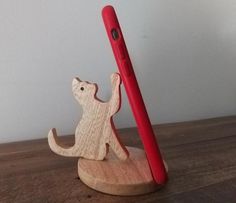 a wooden cat figurine next to a red cell phone