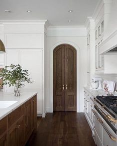 a kitchen with wood floors and white cabinets, along with a wooden door that leads to the dining room