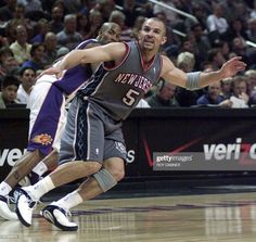 a basketball player dribbling the ball while being guarded by another player in front of an audience