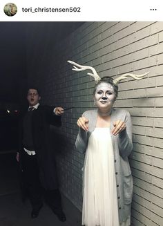 two people dressed in costumes standing next to a brick wall with fake hair and makeup on their faces