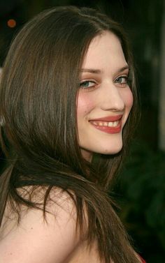 a close up of a person with long hair and a smile on her face, wearing a red dress