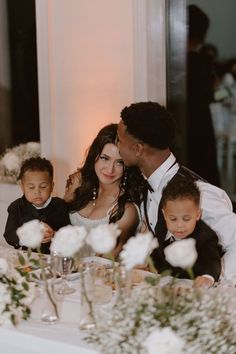 a couple and their children are sitting at a table with flowers in front of them