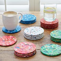 colorful coasters with confetti designs on them and a cup of water in the background