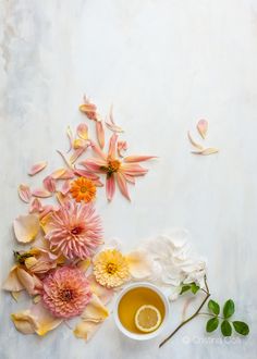 an arrangement of flowers and tea on a white surface