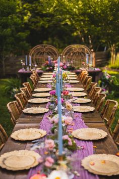 a long table is set with plates and place settings for an outdoor dinner in the garden