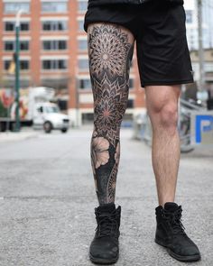 a man with tattoos on his legs and leggings is standing in the street