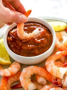 a person dipping sauce on top of shrimp