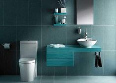 a bathroom with green tile walls and blue countertop, white porcelain sink and toilet