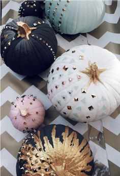 several decorative pumpkins on a chevron tablecloth with gold and black decorations around them