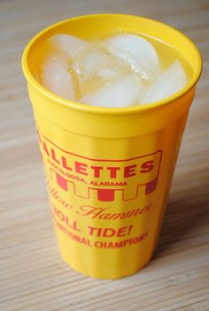 a yellow cup filled with ice on top of a wooden table