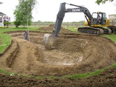 an excavator digging dirt into the ground in front of a house with a tractor