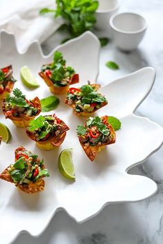 small appetizers on a white platter with limes and garnishes