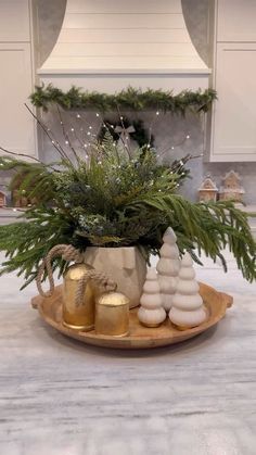 a potted plant sitting on top of a wooden platter filled with christmas decorations