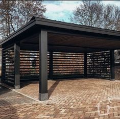 a covered area with brick pavers and trees in the background