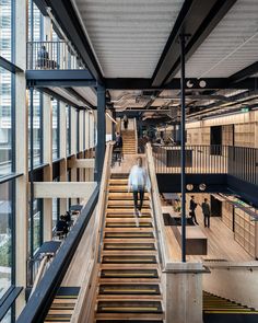 people are walking up and down the stairs in an office building with large windows on both sides