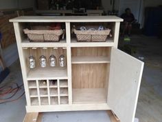 a wooden cabinet with wine glasses and baskets on it's shelves in a garage