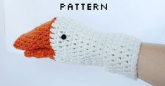 an orange and white knitted glove with the word pattern on it, in front of a person's hand