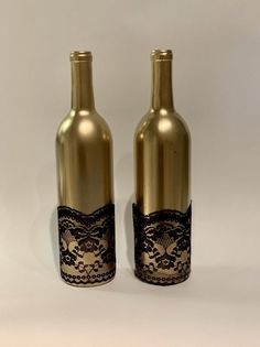 two wine bottles with lace on them sitting next to each other in front of a white background