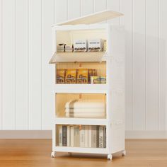 a white book shelf with books and other items in it on top of a wooden floor