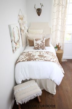 a white bed sitting in a bedroom next to a wall mounted antelope head