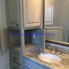 a bathroom vanity with marble counter top and white cabinetry in front of the mirror